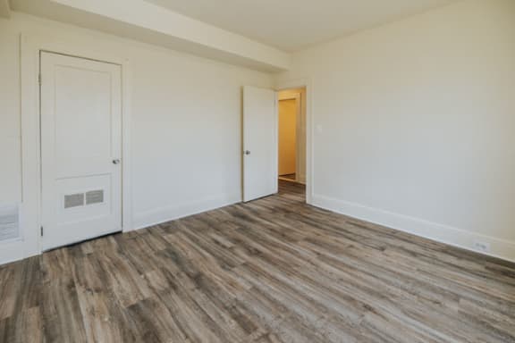 a bedroom with white walls and hardwood floors at Ivy Hall Apartments*, Towson, MD