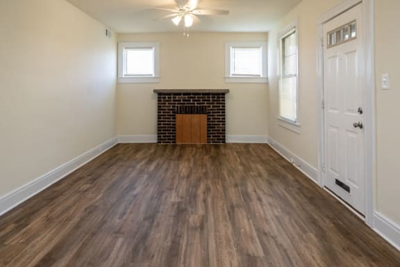 an empty living room with a fireplace and a ceiling fan at Ivy Hall Apartments*, Towson, MD 21204