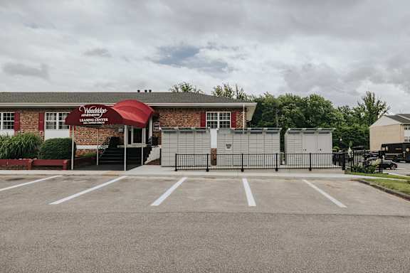 A parking lot in front of a building with a red awning at Deer Park Apartments, Randallstown, 21133