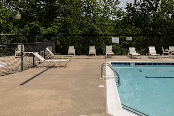 A pool with a fence and chairs around it.