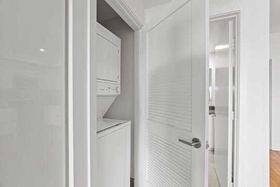 A white door is open to a kitchen.