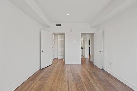 A long hallway with white walls and wood floors.