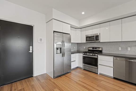 A modern kitchen with stainless steel appliances and wooden floors.