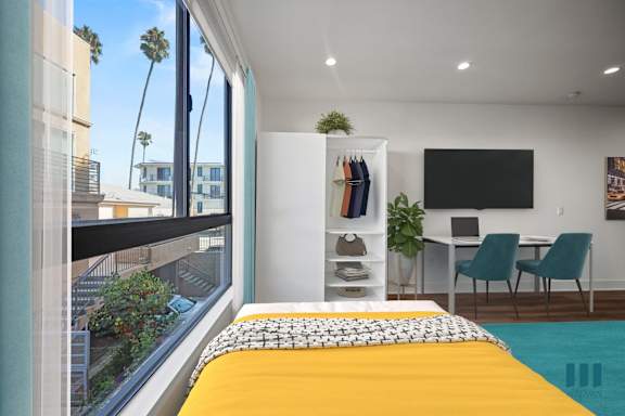 A bedroom with a yellow bedspread and a view of the city.