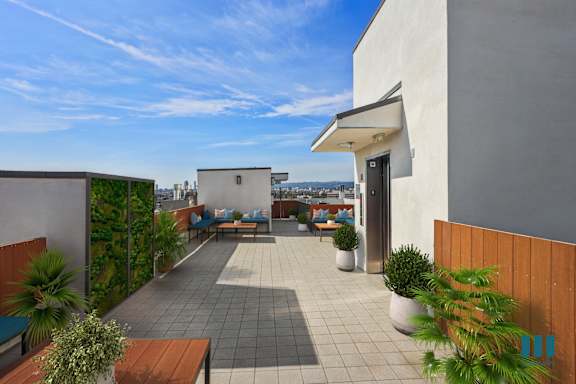 A patio with a table and chairs is surrounded by plants and a wall.