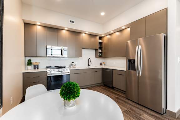 A modern kitchen with a stainless steel refrigerator and a white table with a green plant on it.