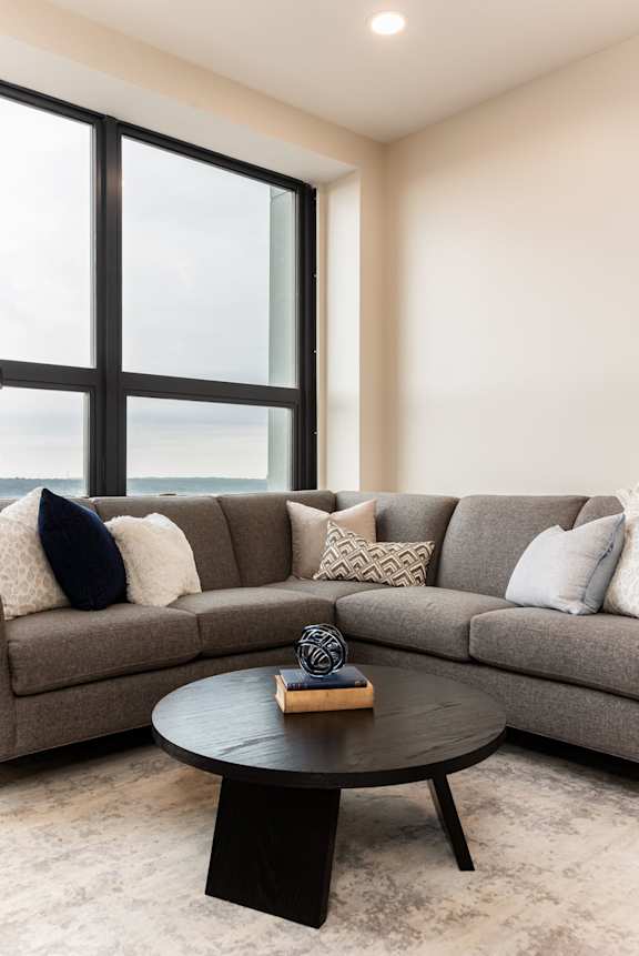 A grey couch with a round table in front of it.