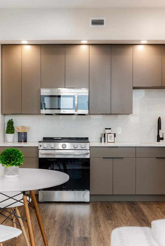 A modern kitchen with a white table and a black stove.