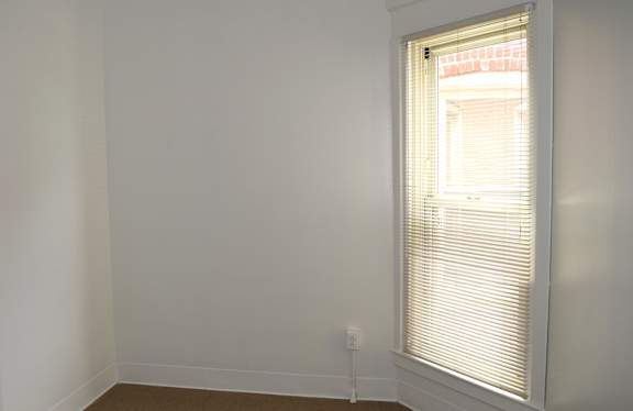 A room with a window and a white wall.