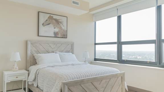 A bedroom with a large bed and a painting of a horse on the wall.