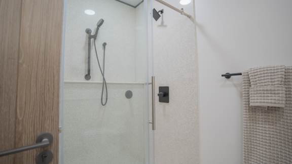 A shower area with a glass door and a towel hanging on the wall.
