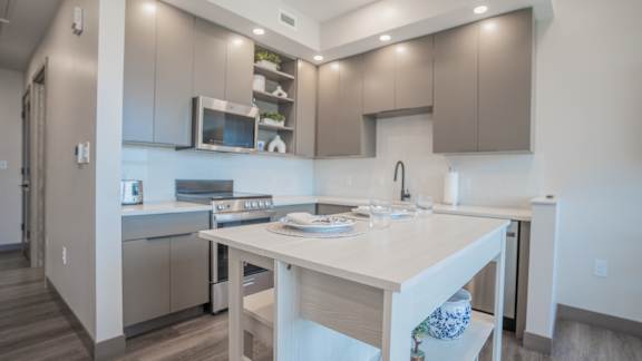 A modern kitchen with a white countertop and stainless steel appliances.