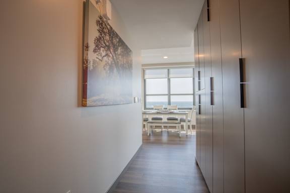 A long hallway with a painting on the wall and a table and chairs in the distance.