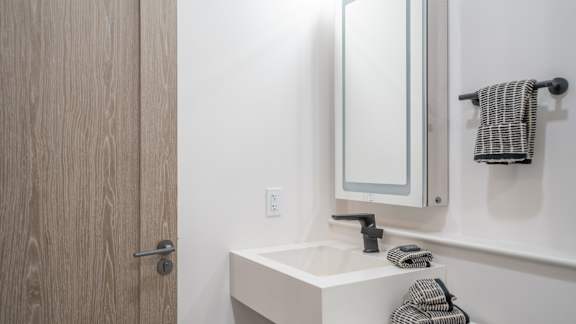 A bathroom with a sink, mirror, and towel.