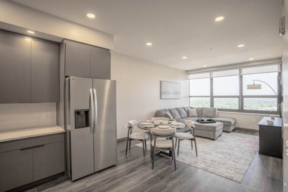 A modern kitchen with a stainless steel refrigerator and a dining table set for four.