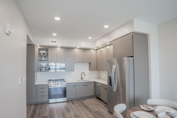 A modern kitchen with a refrigerator, sink, and dining table.