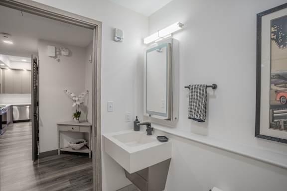 A bathroom with a sink, mirror, and a framed picture on the wall.