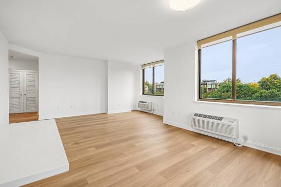A large empty room with wooden floors and white walls.