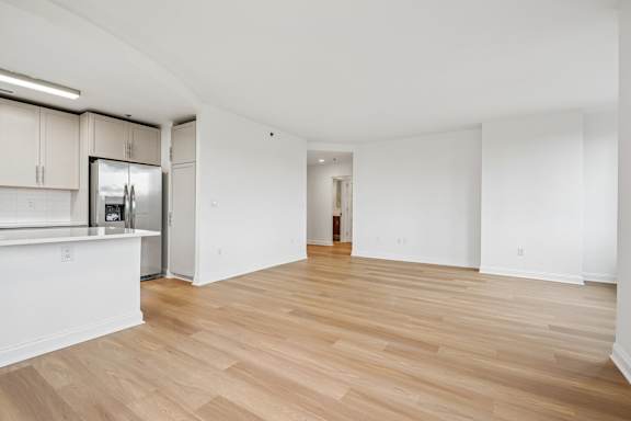 A spacious room with wooden flooring and white walls.