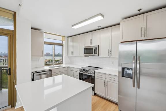 A modern kitchen with stainless steel appliances and white countertops.