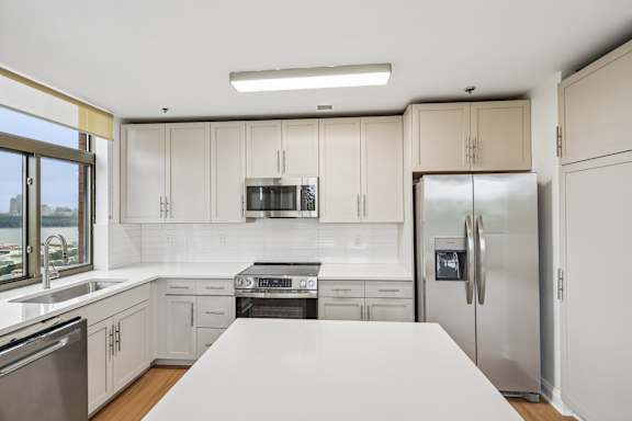 A modern kitchen with stainless steel appliances and white cabinets.