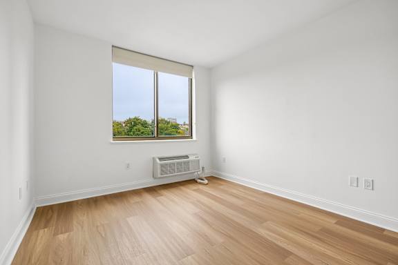 A room with a window and a wall-mounted air conditioner.