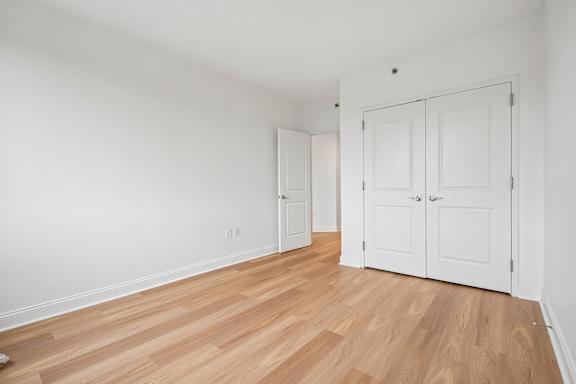 A room with white walls and wooden flooring with two white doors.