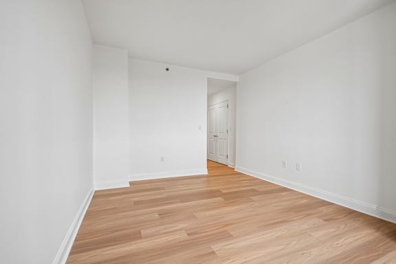 Empty room with wooden flooring and white walls.
