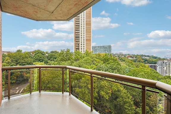 A balcony with a view of a road and trees.