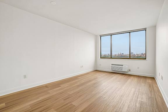Empty room with wooden floor and large window.