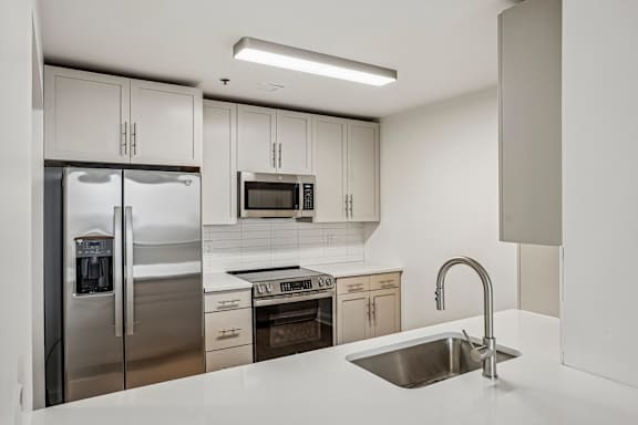 A modern kitchen with a stainless steel refrigerator, microwave, and oven.