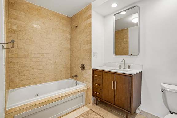 A bathroom with a tub, sink, and mirror.