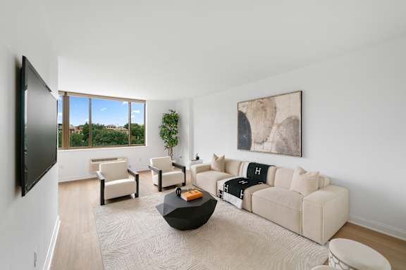 A living room with a large couch, a coffee table, and a flat screen TV.