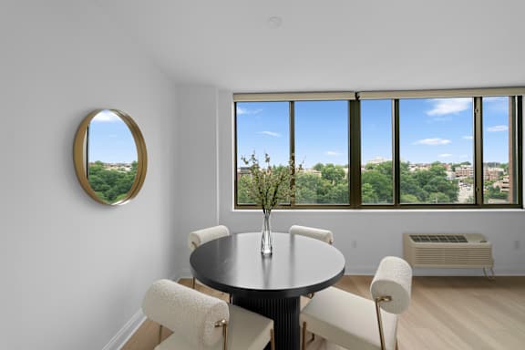 A round table with a vase of flowers on it sits in a room with a large window.