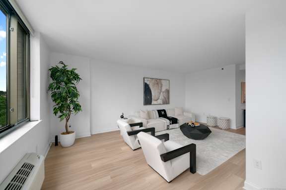 A living room with white furniture and a large window.