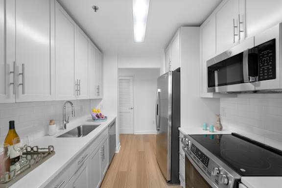 A modern kitchen with white cabinets and stainless steel appliances.