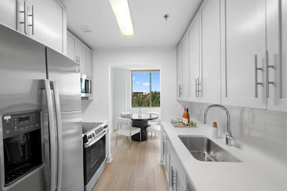 A modern kitchen with stainless steel appliances and white cabinetry.