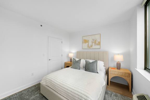 A bedroom with a large bed, nightstand, and lamp.