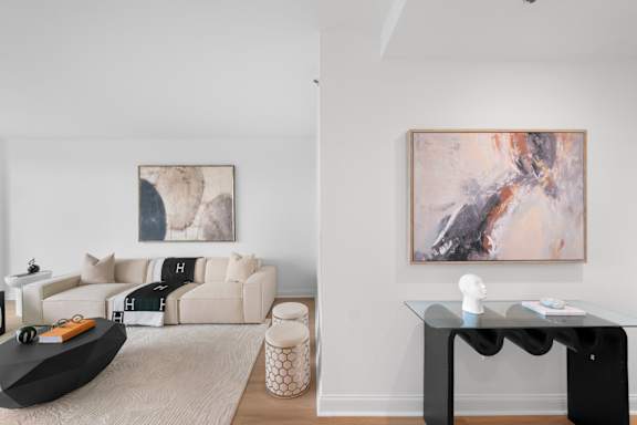 A modern living room with a black table and a painting on the wall.