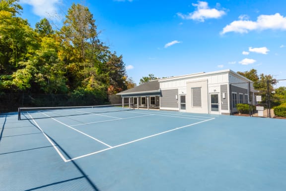 a large tennis court in front of a house with a tennis court