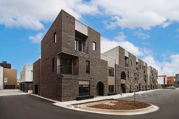 A row of modern brick apartment buildings are lined up on a street.