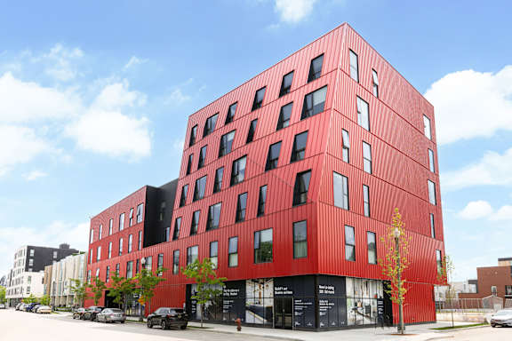 A red building with black windows and a tree in front of it.