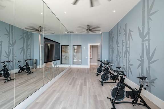 A room with exercise bikes and mirrors on the wall