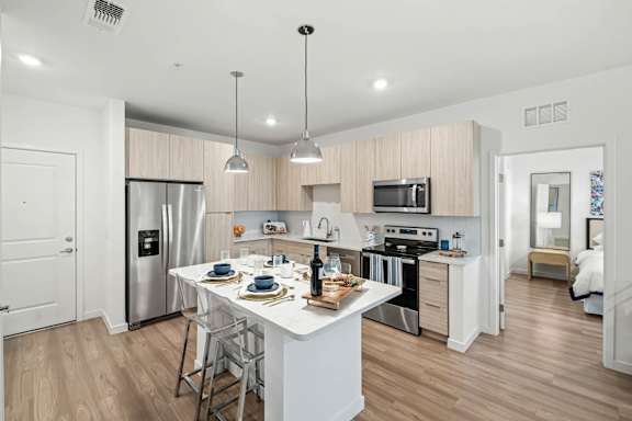 A modern kitchen with a dining table set for two.