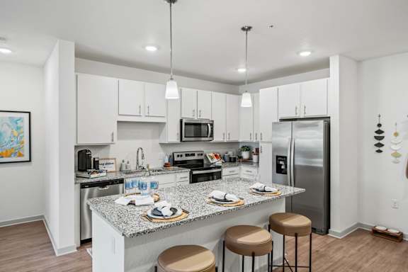 A kitchen with a granite countertop and stainless steel appliances.