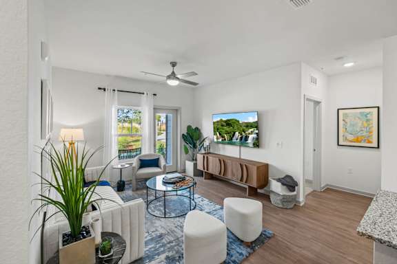 A living room with a couch, a chair, a table, a potted plant, and a painting on the wall.