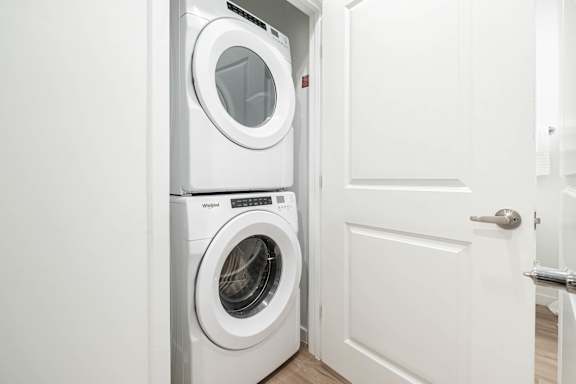 A white door is open to a laundry room with a washer and dryer.