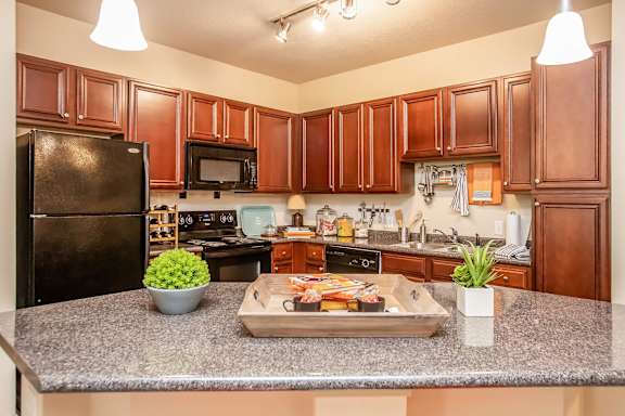 A kitchen with brown cabinets and a black refrigerator.