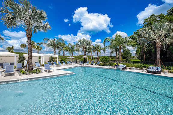 A large swimming pool surrounded by palm trees and lounge chairs.at Altis Grand Twin Lakes, Florida, 34744