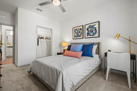 A bedroom with a bed, two lamps, a chair, and two pictures on the wall.